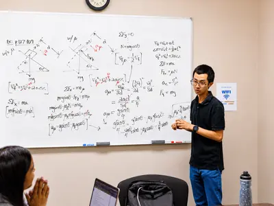 Instructor teaching physics lesson at a whiteboard