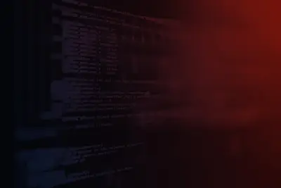 Computer screen displaying lines of programming code, dimly lit with a dark red glow.
