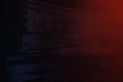Computer screen displaying lines of programming code, dimly lit with a dark red glow.