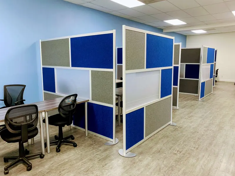 Study area with blue and gray modular partition walls separating desks with black rolling chairs