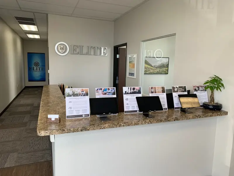 Office lobby with a granite reception counter holding monitors and flyers for SAT Prep, ACT Prep and counseling, under an "ELITE" wall sign.