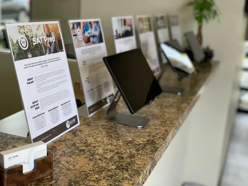 A granite front counter lined with "SAT Prep" flyers, a tablet on a stand, and business cards in a holder.