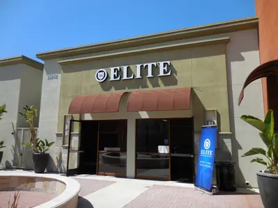 Storefront of an Elite Educational Institute branch with awning, glass doors, and a blue Elite banner outside.