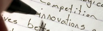 A pen resting on lined paper with handwritten words including "competition," "innovations" and "better".