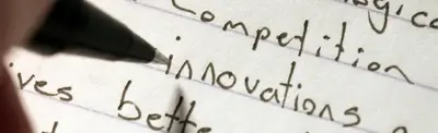 A pen resting on lined paper with handwritten words including "competition," "innovations" and "better".