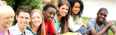 A diverse group of smiling teenagers sitting together outdoors on the grass