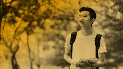 A smiling student with a backpack and a notebook, outdoors among trees