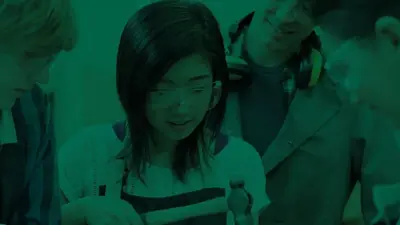 A student in safety glasses working on a project with her classmates