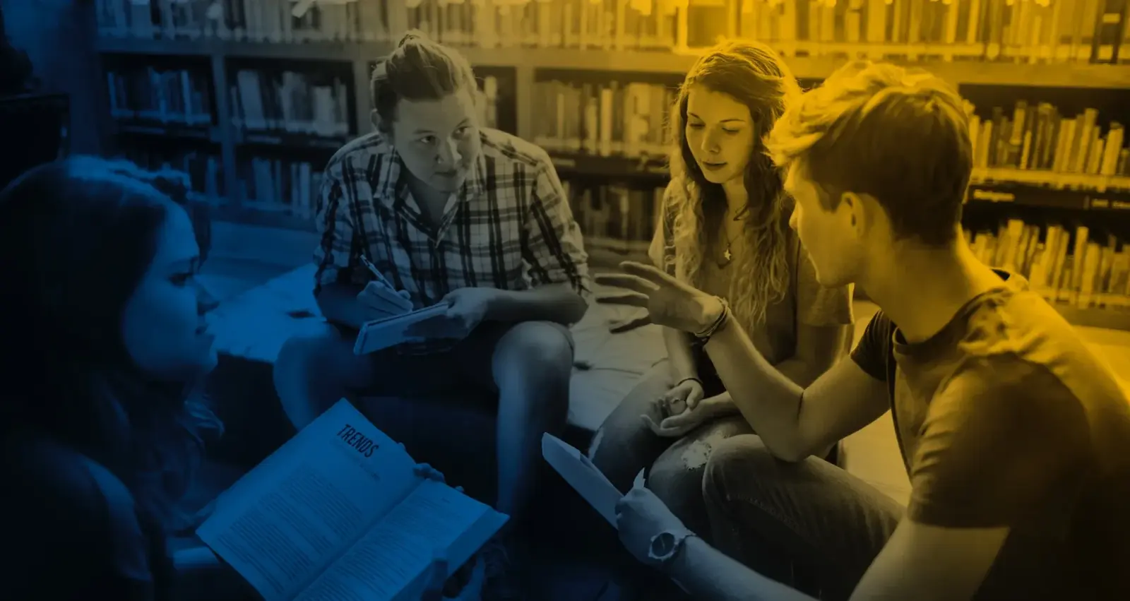 Four students talking over their notes in a library