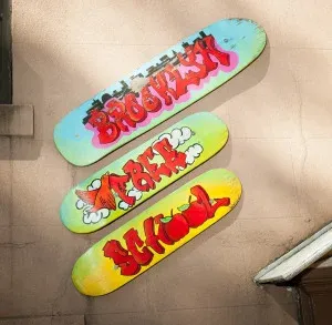 Three colorful graffiti-painted skateboard decks mounted on a beige stucco wall