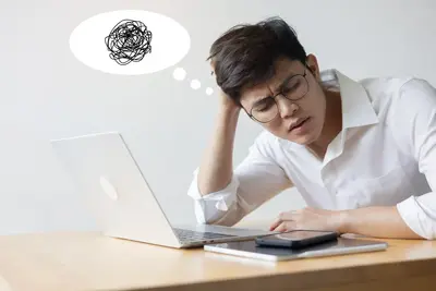 A frustrated student rests his head on his hand at a laptop, with a scribbled thought bubble above him.