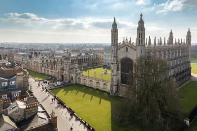 Aerial view of a Gothic university chapel with spires overlooking green lawns and historic college buildings