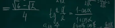 Chalkboard with handwritten trigonometry work including (\u221a6 \u2212 \u221a2)/4 and tg\u00b2(\u03b1/2) = (1 \u2212 cos\u03b1)/(1 + cos\u03b1).