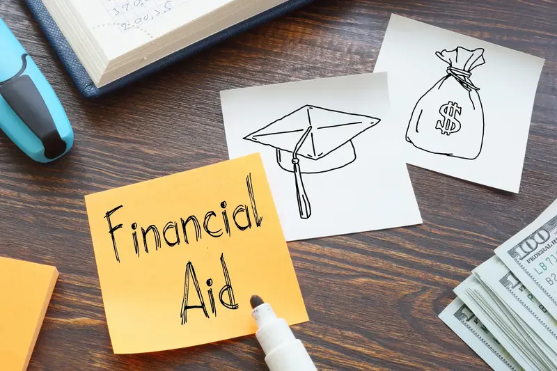 Orange sticky note reading "Financial Aid" beside sketches of a graduation cap and money bag, a marker, and cash.