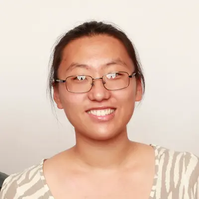 안경을 쓴 여성이 칠판에 분필로 그려진 책, 원자, 필름 모양의 생각 풍선을 올려다보고 있는 모습
