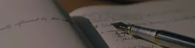 A fountain pen resting on an open notebook filled with handwritten notes and a numbered list.