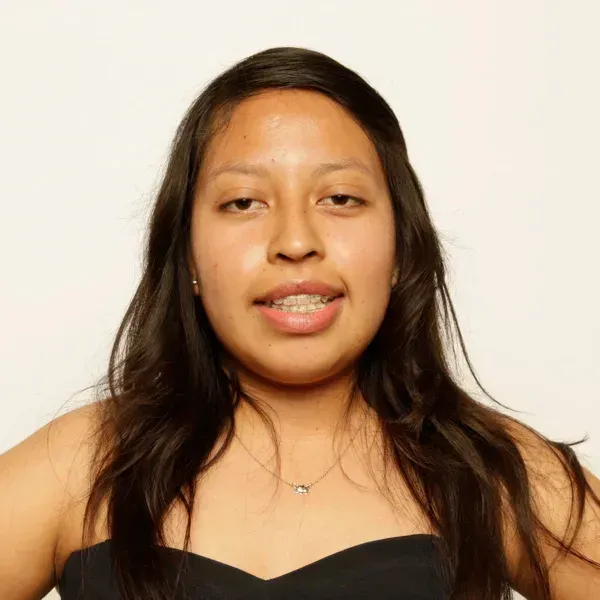 Portrait of a smiling young woman with long dark hair wearing a black strapless top and a necklace