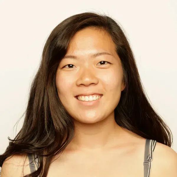 Smiling young woman with long dark hair, in a portrait against a plain light background