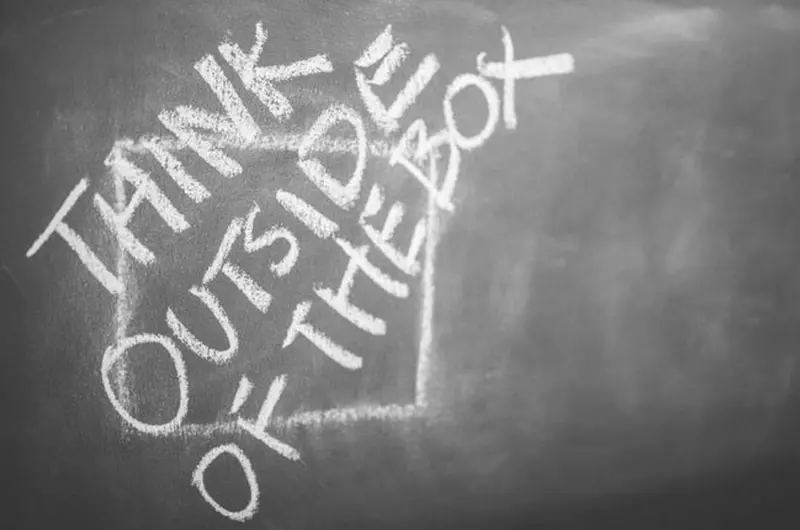 Chalkboard with "Think outside of the box" written in chalk across a drawn square