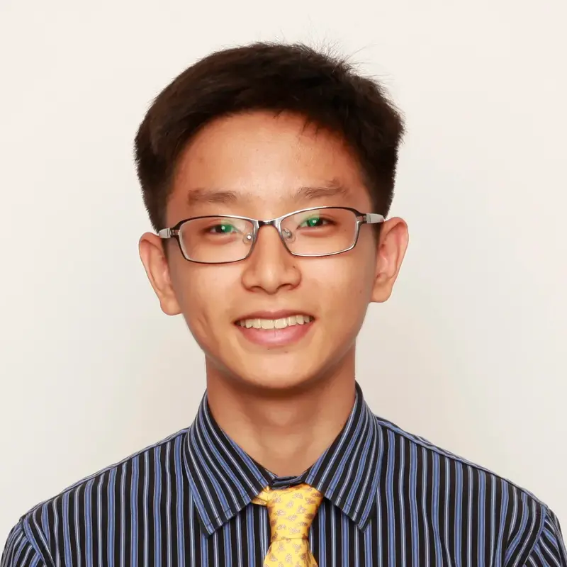 Smiling young man with glasses wearing a striped shirt and yellow patterned tie