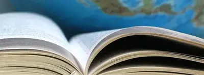An open book with fanned pages in front of a blurred world globe