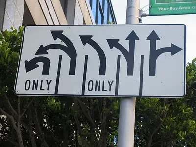 Road sign with arrows for five lanes, two marked "ONLY," showing left, straight and right turn options.