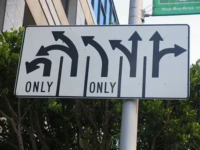 Road sign with arrows for five lanes, two marked "ONLY," showing left, straight and right turn options.