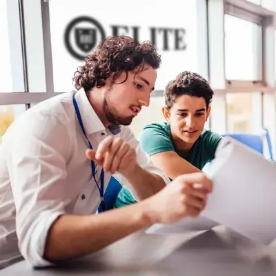 An Elite Prep tutor going over a paper with a student, the Elite sign behind them